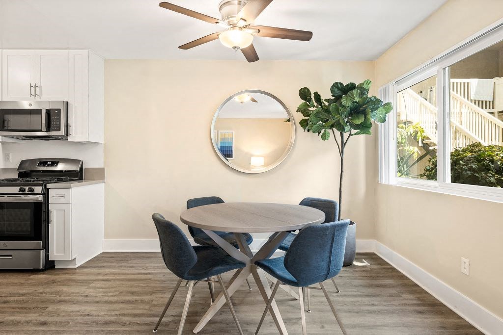Dining Room with Round Dinner Table, Blue Chairs, Tall Potted Plant, and Ceiling Fan at Casa De Marina Apartments, Los Angeles, California