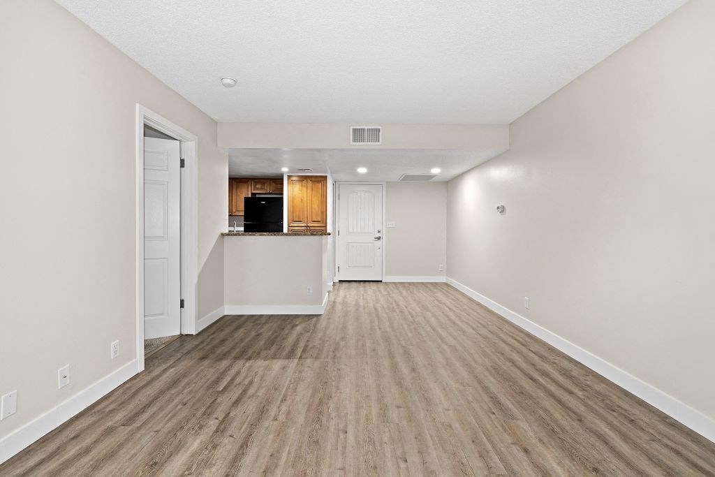 an empty living room with a kitchen in the background at Woodland Trio Apartments, North Hollywood, CA, 91601