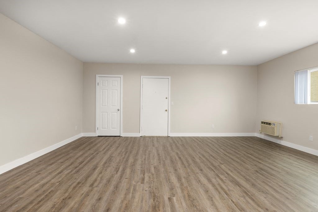 a bedroom with a hardwood floor and white walls