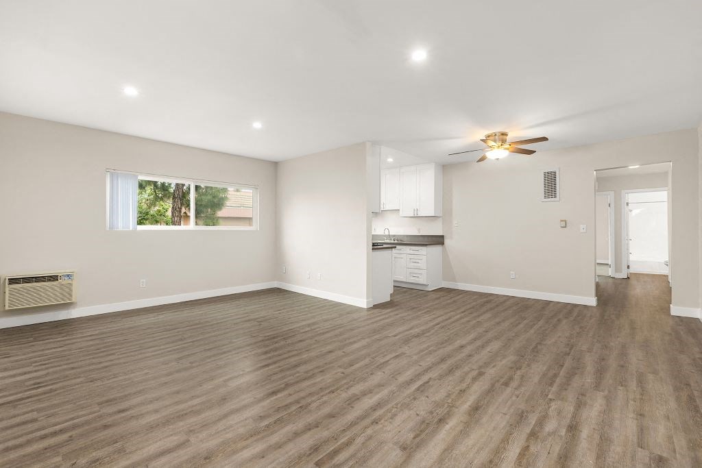 an empty living room with a kitchen in the background