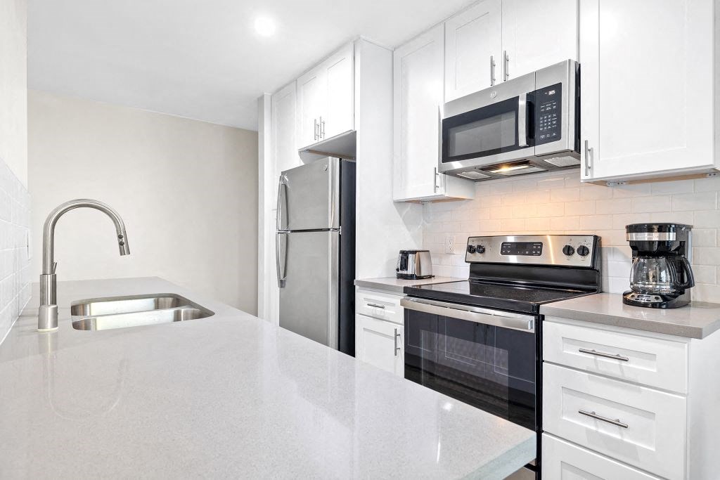 Kitchen Area with Stainless-Steel Appliances, White Modern Cabinets, and Quartz Countertops at Brookside Terrace Apartments, Encino