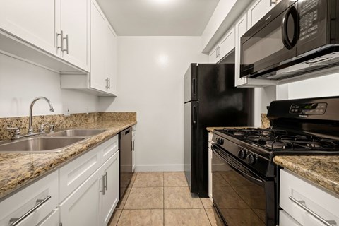 A kitchen with a black refrigerator and stove top oven.