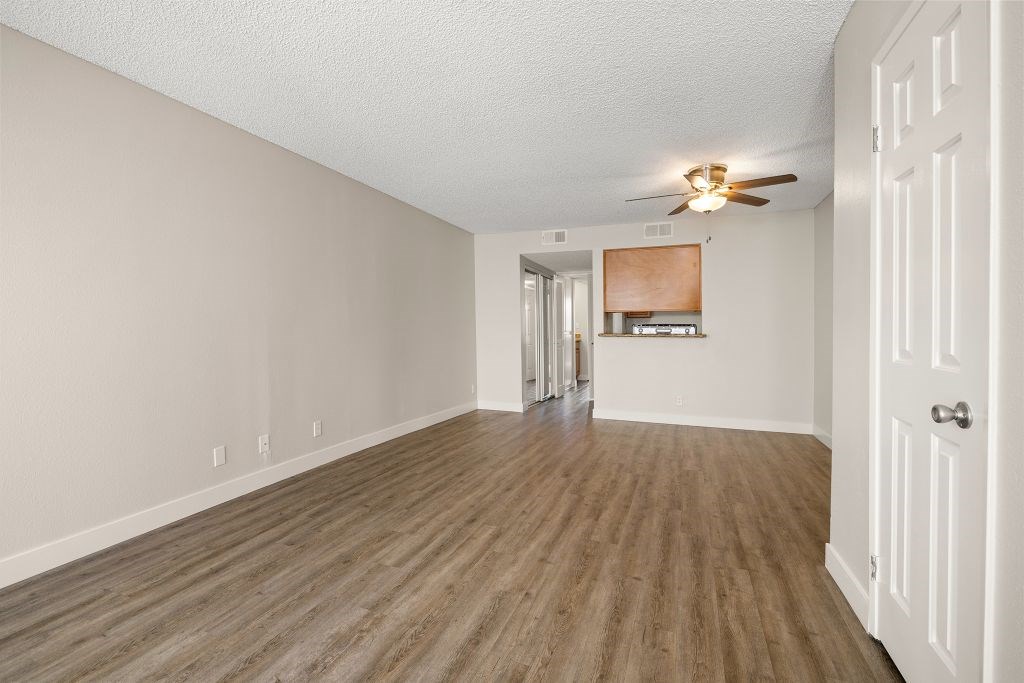 A room with a ceiling fan and wooden flooring.