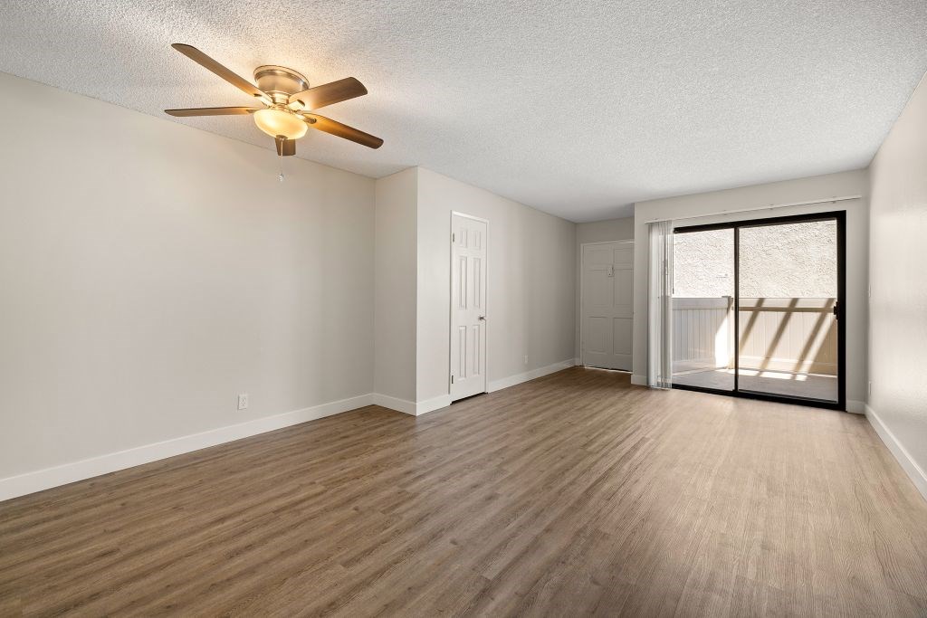A room with a ceiling fan and wooden flooring.