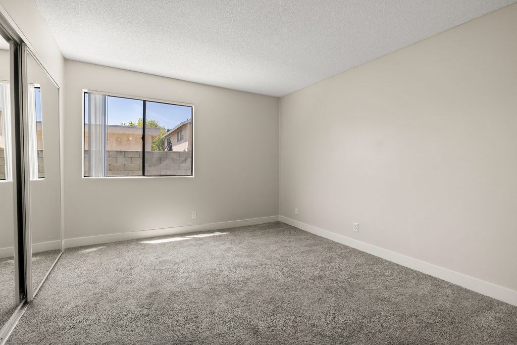 A room with a carpeted floor and a window.