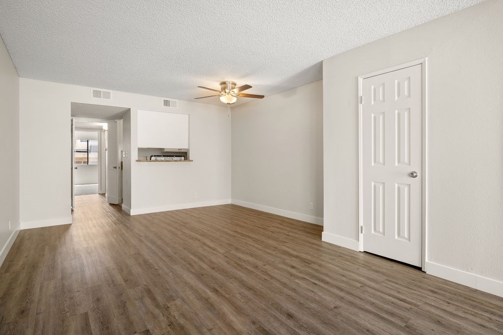 A room with a ceiling fan and wooden flooring.