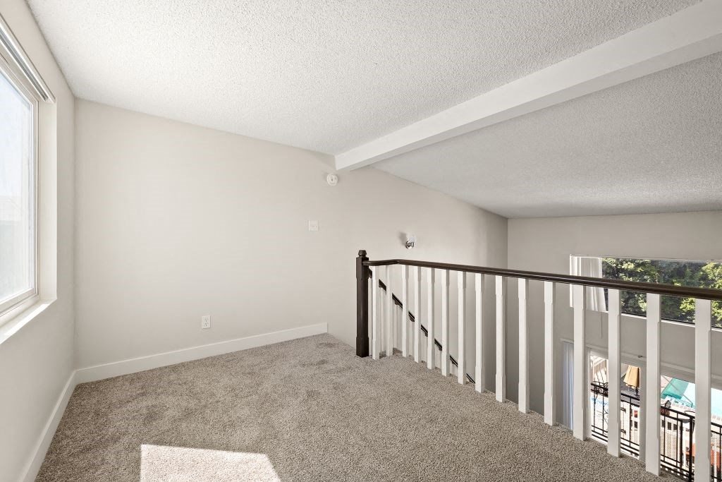the upstairs loft of a house with carpeted stairs and a window