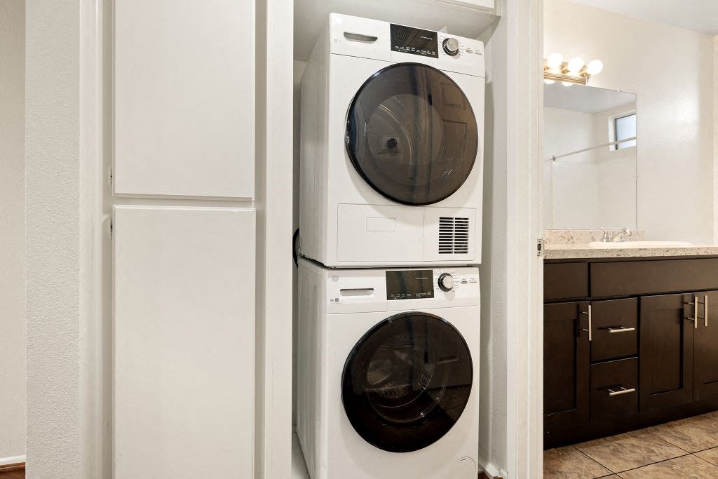 A white front loading washing machine is stacked on top of a smaller white top loading washing machine.
