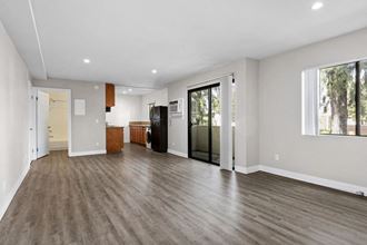 a living room with a hardwood floor and a door that leads to a kitchen