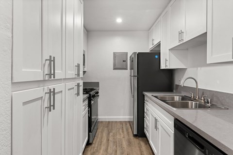 A kitchen with white cabinets and a black refrigerator.