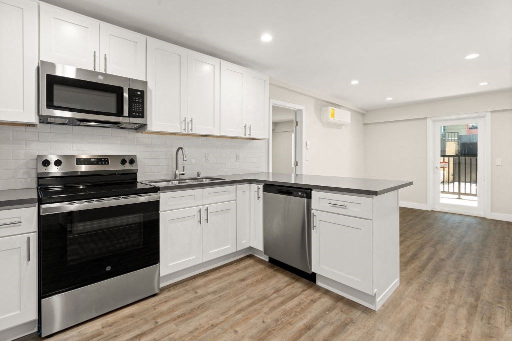 a kitchen with white cabinets and a stove and a microwave at Woodland Trio Apartments, North Hollywood, CA