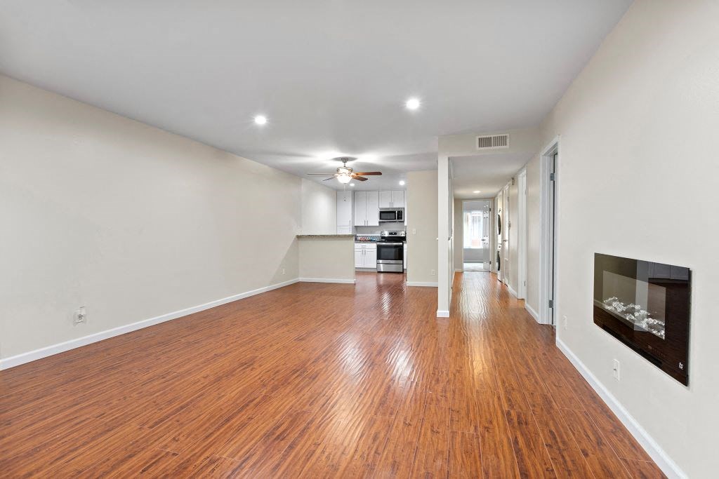 a living room with a fireplace and a kitchen in the background at The Meadows at Westlake Village Apartments,Westlake Village, California