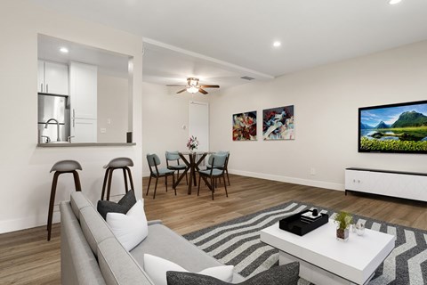 A modern living room with a grey sofa, a white coffee table, and a television on the wall.