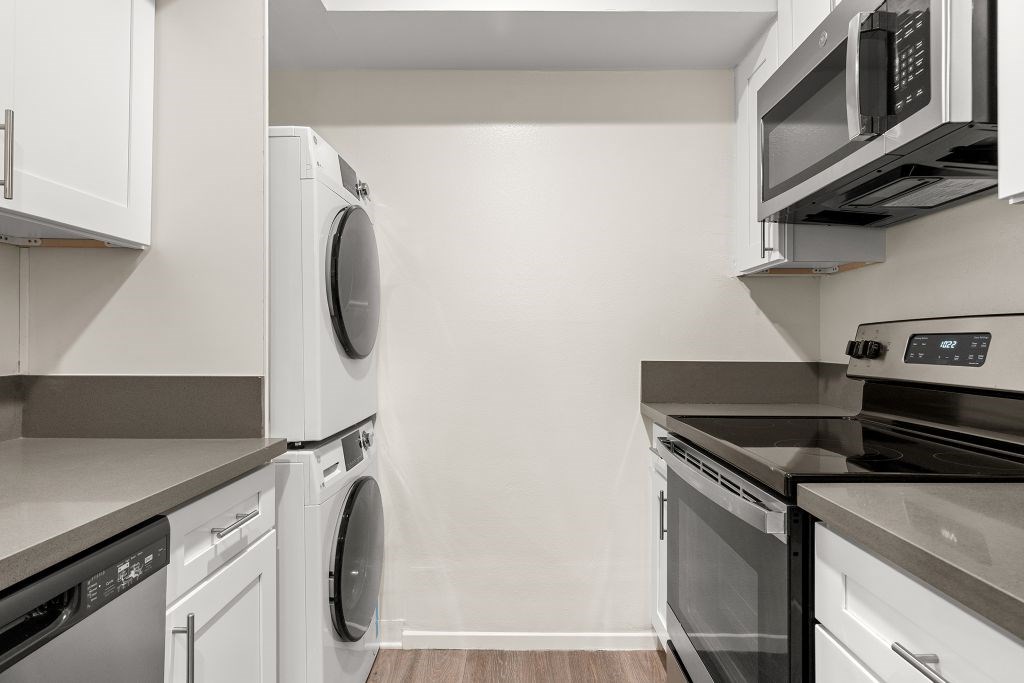 A modern kitchen with white cabinets and stainless steel appliances.