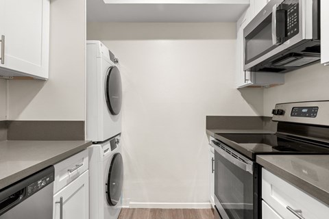 A modern kitchen with white cabinets and stainless steel appliances.