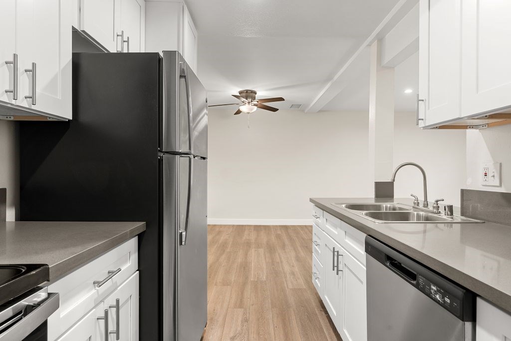 A kitchen with white cabinets and a black refrigerator.