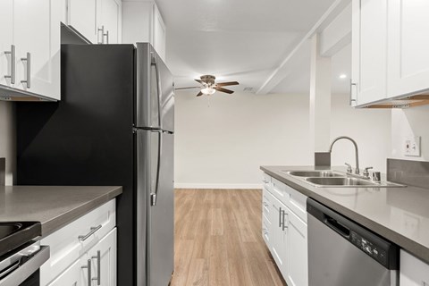 A kitchen with white cabinets and a black refrigerator.