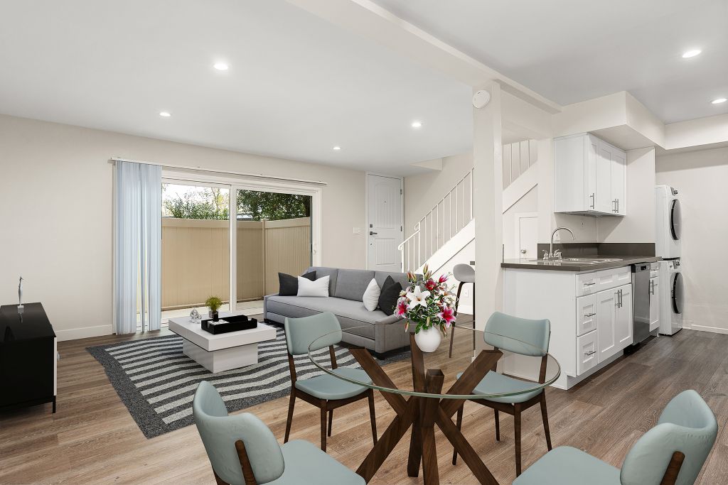 A modern living room with a glass table and grey chairs.