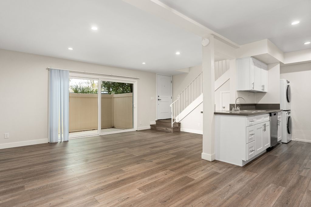 A kitchen with white cabinets and a wooden floor.