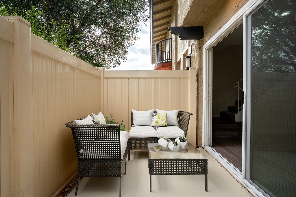 A patio with a chair and a table with a glass top.