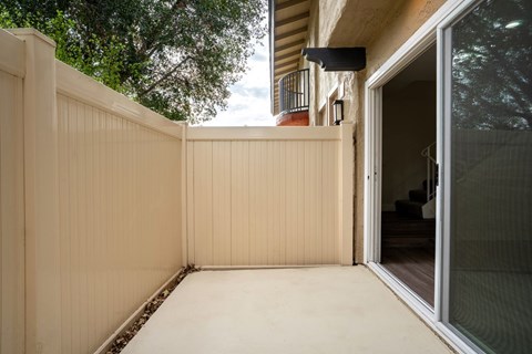 A patio with a sliding glass door and a slat fence.