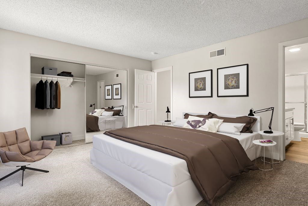 A bedroom with a large bed and a chair.