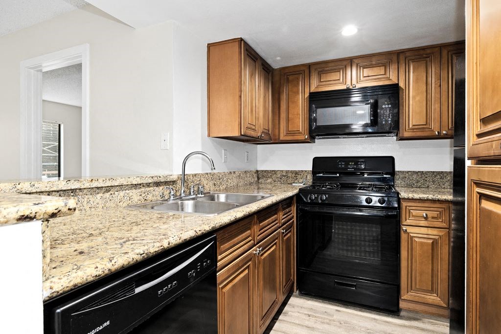 a kitchen with wooden cabinets and a black stove top oven at Woodland Trio Apartments, North Hollywood