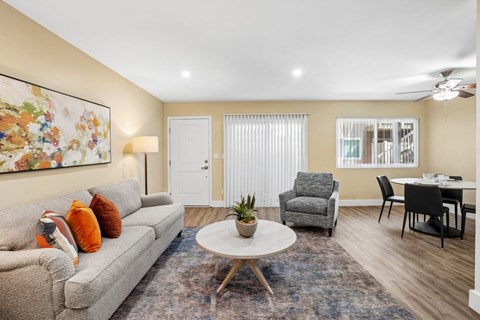 A living room with a grey couch, a white coffee table, and a painting on the wall.