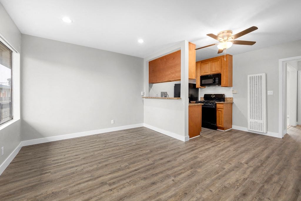 an empty living room with a kitchen in the background at Riverside Villas Apartments, Valley Village, California