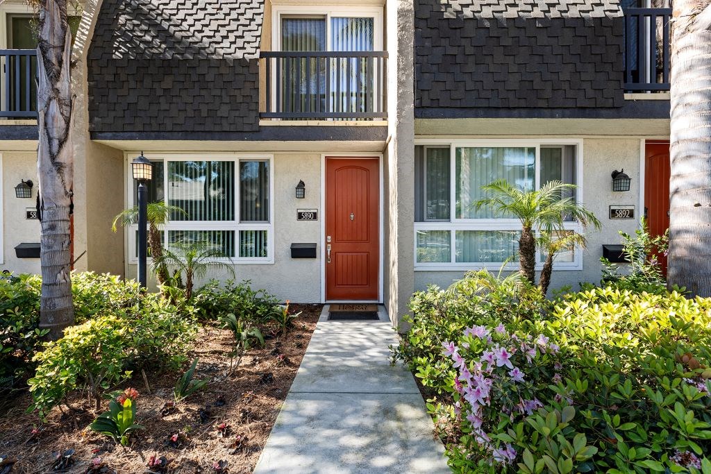 a sidewalk in front of a house with a red door