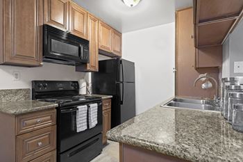 a kitchen with black appliances and granite counter tops at Vista Apartments, Mar Vista, California