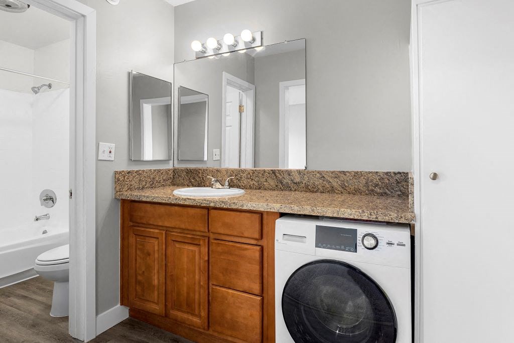 a bathroom with a sink and a washer and dryer at Riverside Villas Apartments, Valley Village, CA