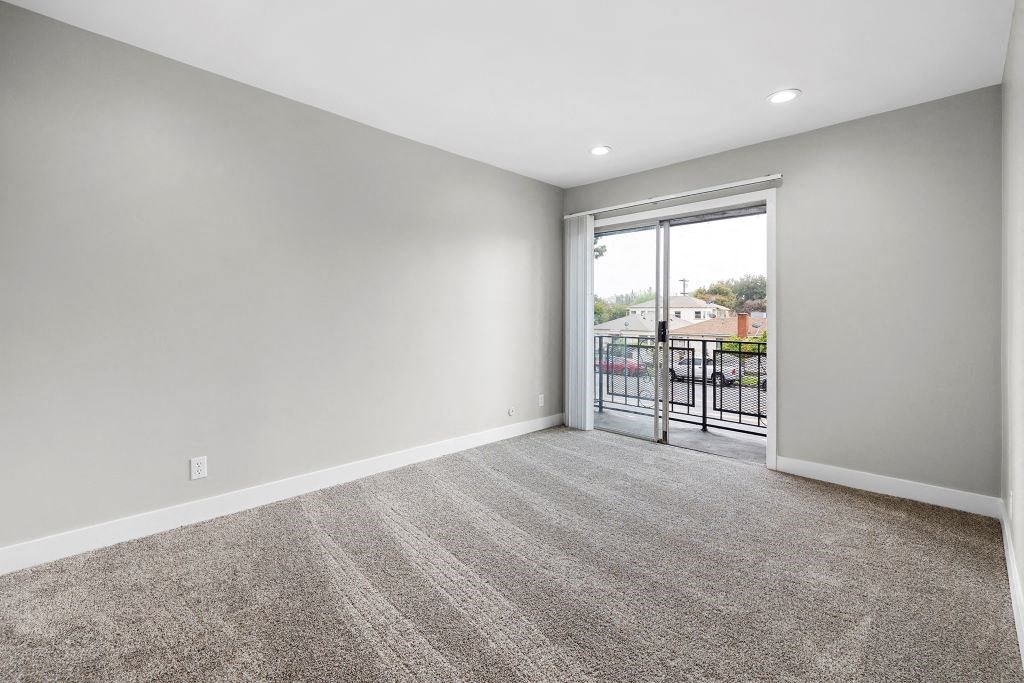a bedroom with a sliding glass door and a carpeted floor at Riverside Villas Apartments, Valley Village, CA