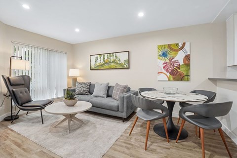 A living room with a grey couch, a white coffee table, and a painting on the wall.