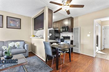 a living room with a table and a kitchen with a ceiling fan at Riverside Villas Apartments, Valley Village, California