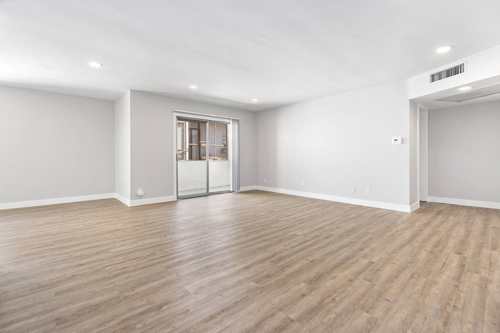 an empty living room with white walls and wood flooring