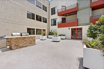 A courtyard with a stone wall and potted plants at Woodland Trio Apartments, California.