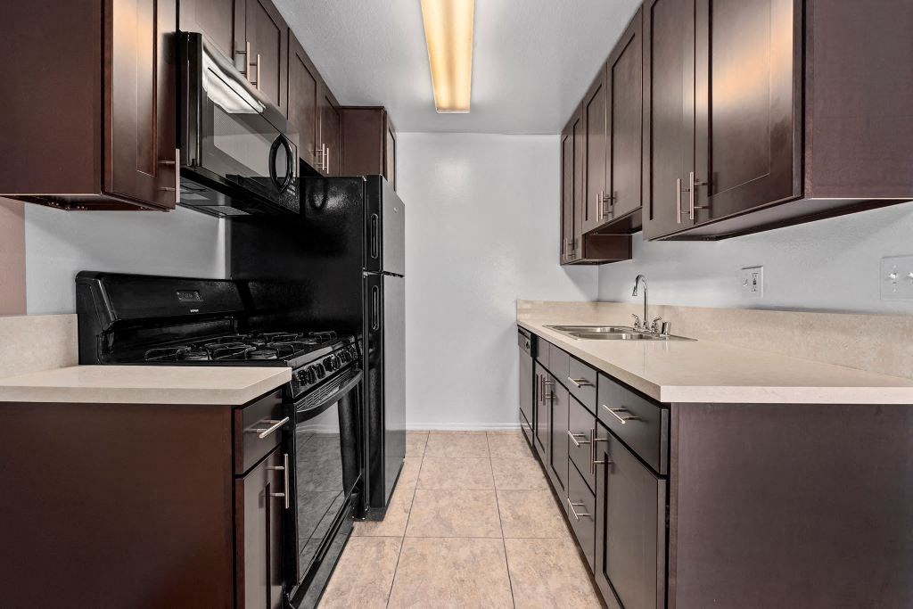 a kitchen with dark cabinets and a black stove top oven