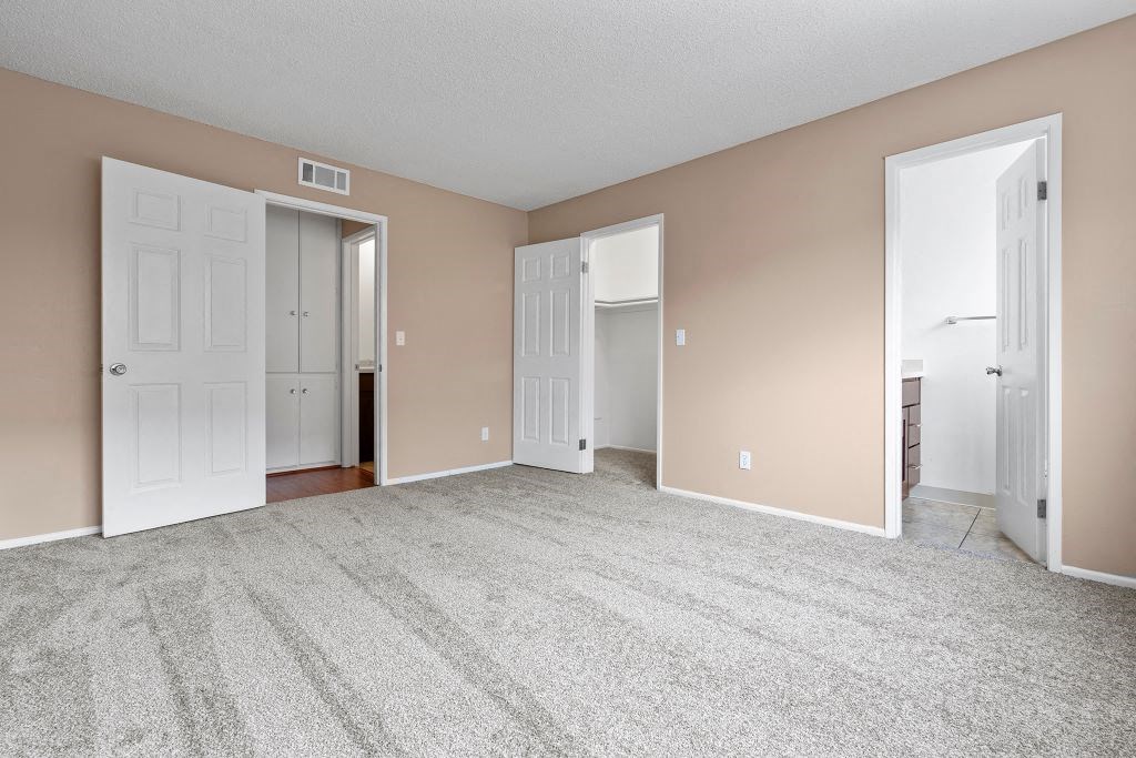 a bedroom with two doors and a carpeted floor
