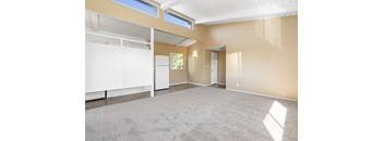 an empty living room with a carpeted floor and a window