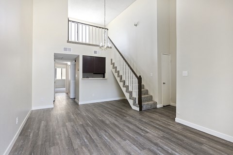 the living room and entryway of a new home with white walls and wood floors