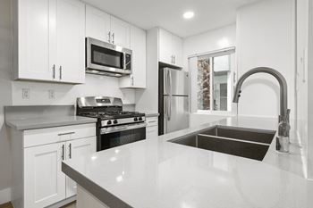 a white kitchen with a large counter top and a sink