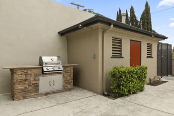 A small house with a red door and a BBQ grill on a stone base.