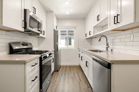 A kitchen with white cabinets and a stainless steel dishwasher.