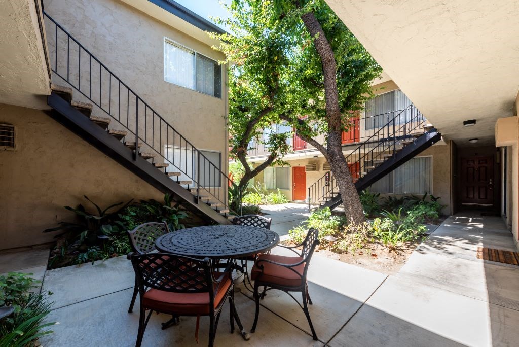 Apartments in Sherman Oaks for Rent - Parkview Terrace - A Table And Chairs In The Outdoor Breezeway Surrounded By Beautiful Landscape