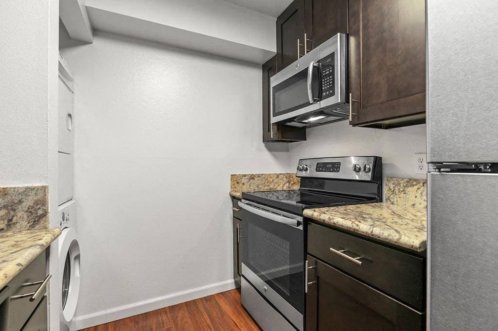 Kitchen with White Walls, Stainless Steel Appliances, Marble Countertops, and Espresso Cabinetry at The Meadows at Westlake Village, California