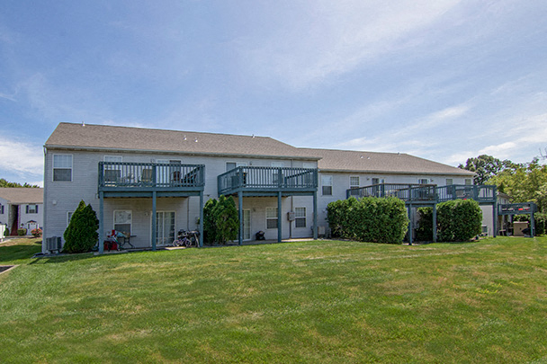 the backyard of a large white house with a green lawn