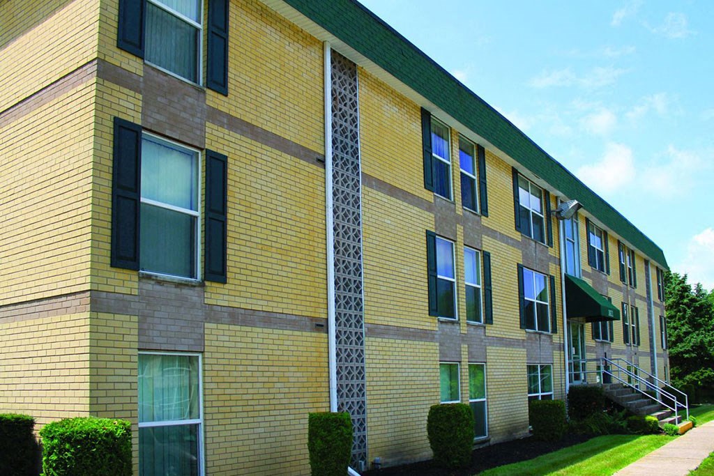 a yellow brick building with a glass column in the front