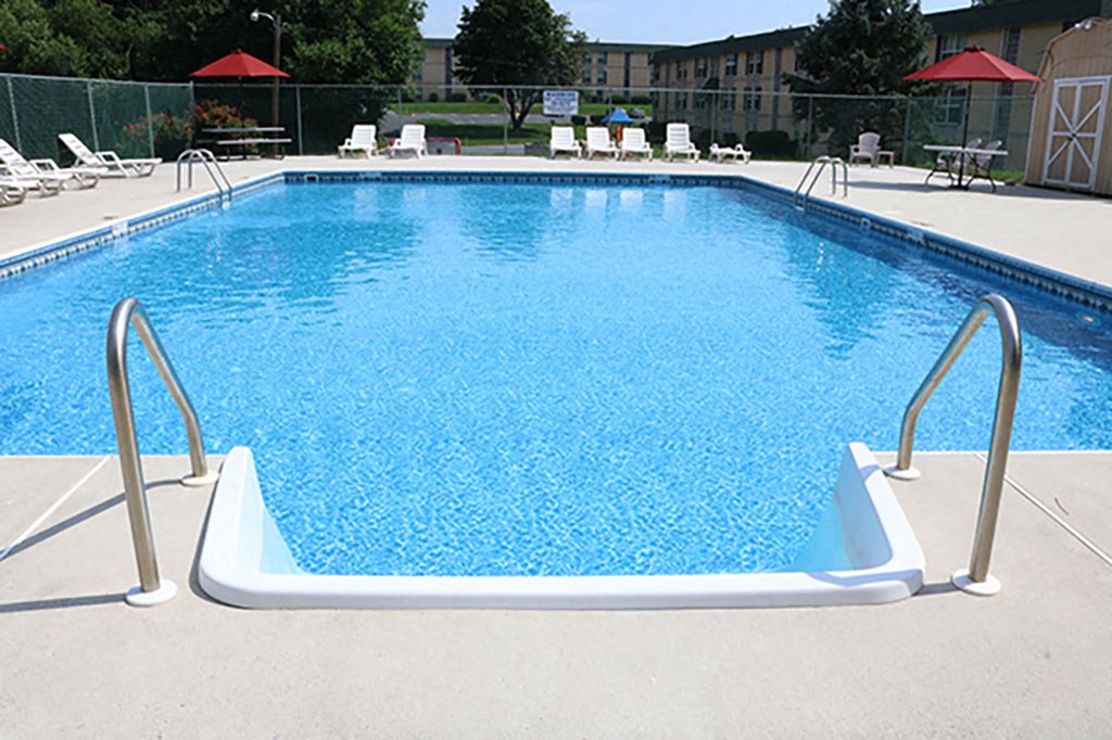 a swimming pool at a resort with chairs and umbrellas
