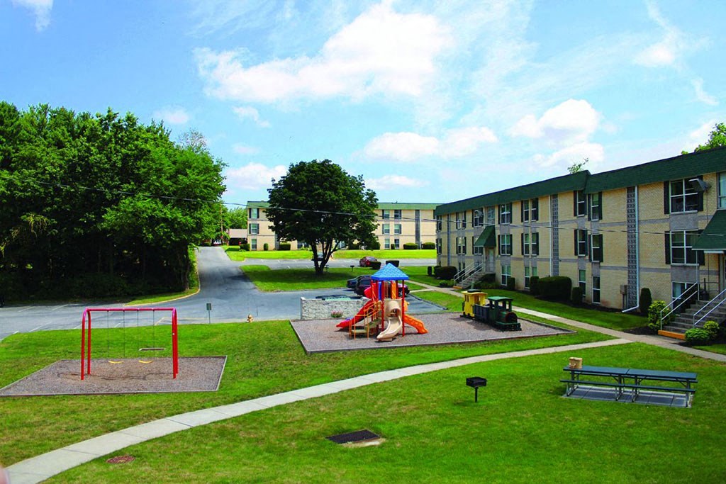 two children playing on a playground in front of an apartment building